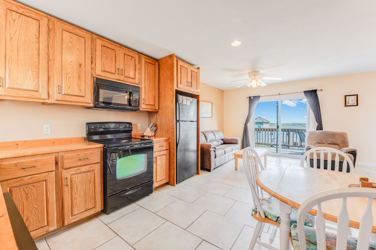 Your spacious kitchen flows seamlessly into the living area, where warm wood cabinets and modern appliances create the perfect space for preparing meals together.