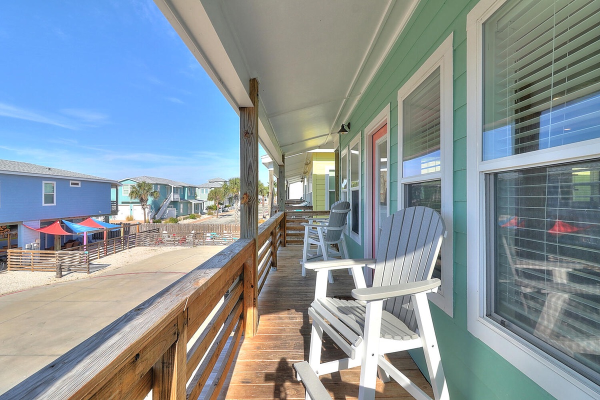 Relax in your coastal rocking chairs on this sunny deck, watching beach life unfold below while gentle ocean breezes keep you cool.