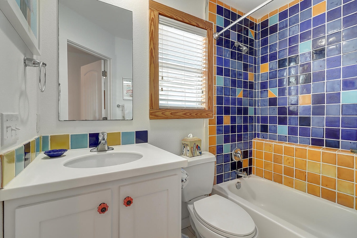 Your vibrant full bathroom features cheerful blue and orange tiles that create a welcoming Mediterranean atmosphere for refreshing moments.