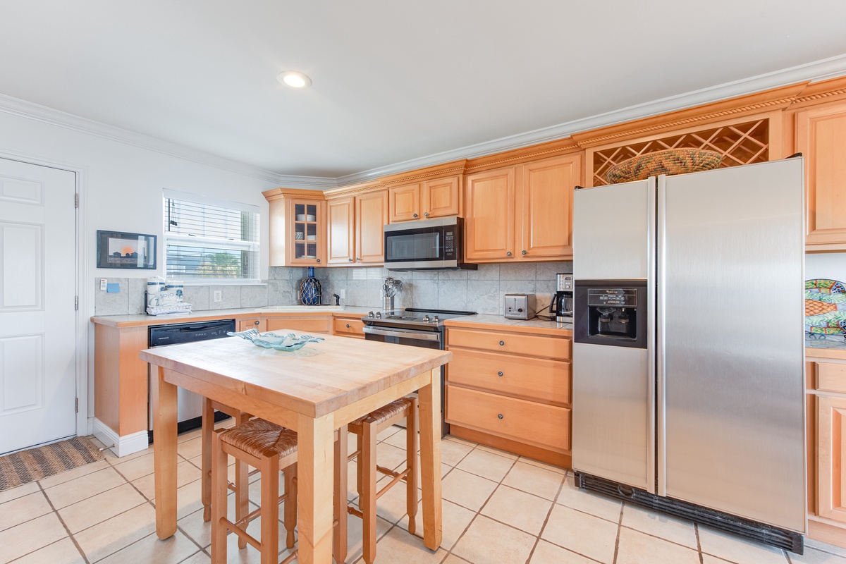 Your fully equipped kitchen features warm wood cabinetry, stainless steel appliances, and a charming island where you can prepare meals together.