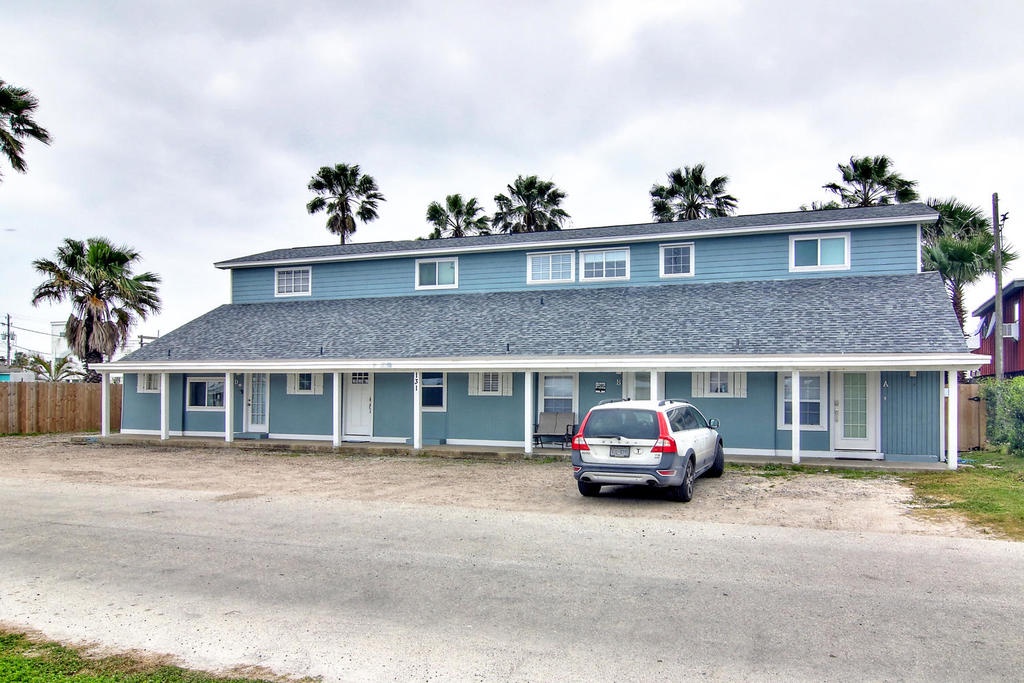 Coastal vacation property featuring tropical charm with palm trees and convenient parking in a relaxed beach community setting.