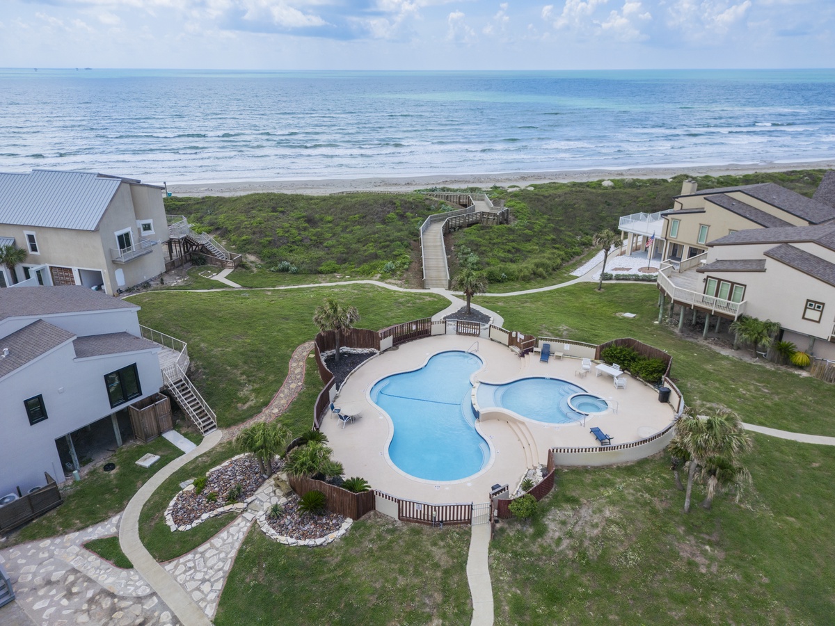 Beachfront vacation community with pool complex and stunning ocean access via elevated walkways through natural dunes.