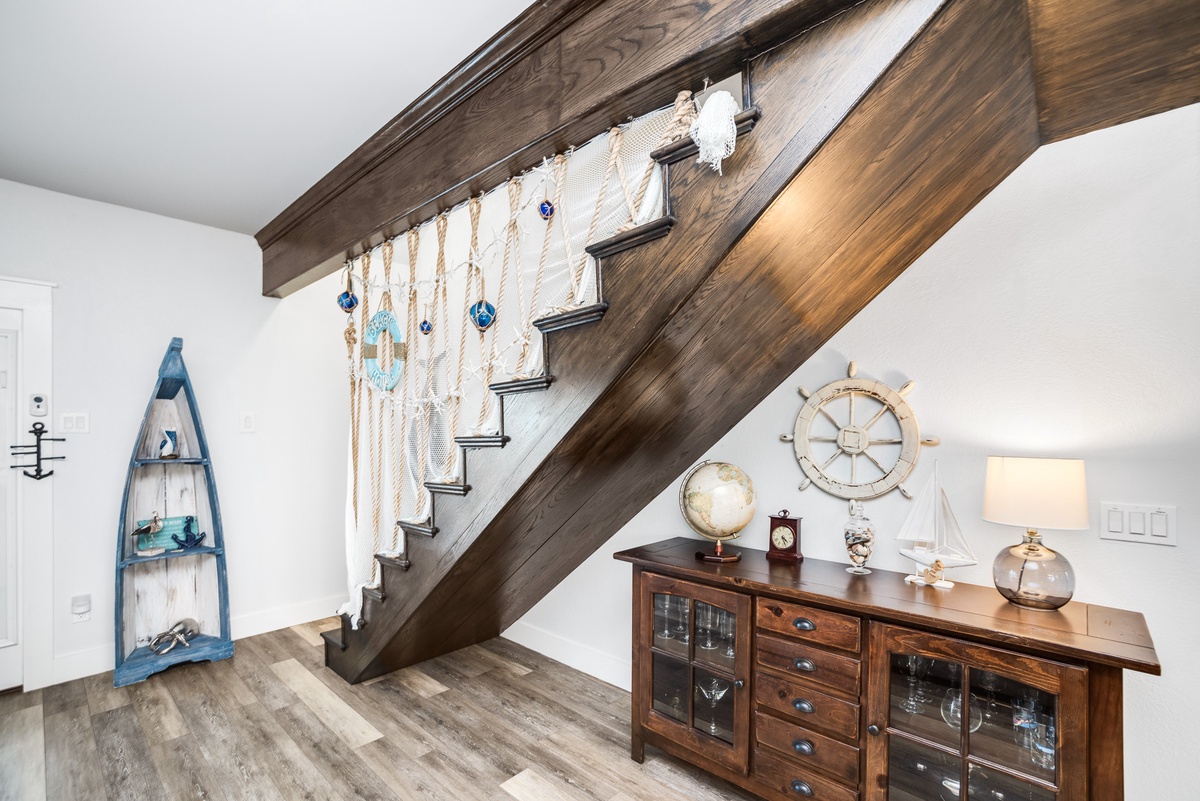 Discover nautical charm beneath your stairway - warm wood tones and maritime treasures create a cozy corner for relaxation.
