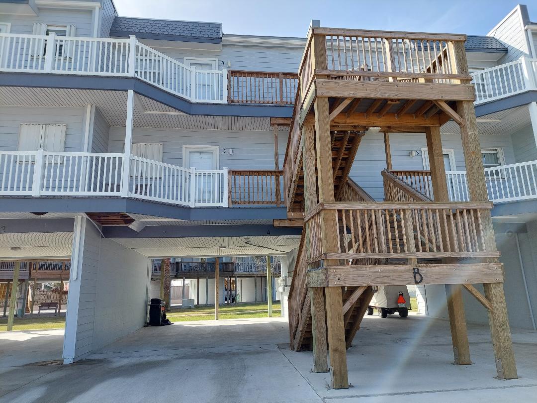 Elevated beachside property with covered parking and sturdy wooden staircases leading to multiple levels of accommodations.