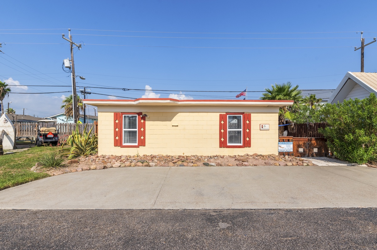 Charming beachside cottage with distinctive coral shutters and tropical landscaping in a quiet residential neighborhood.