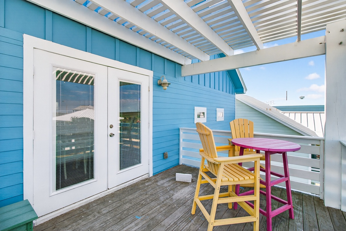 Your private balcony beckons with cheerful yellow chairs and a pop of pink—perfect for morning coffee or sunset cocktails with ocean breezes.