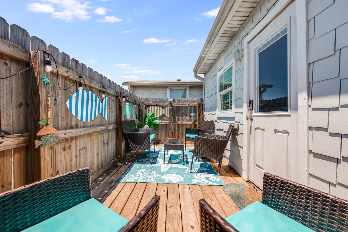 Step onto your private deck where coastal charm meets comfort. Relax in wicker seating surrounded by playful nautical decor and twinkling lights.