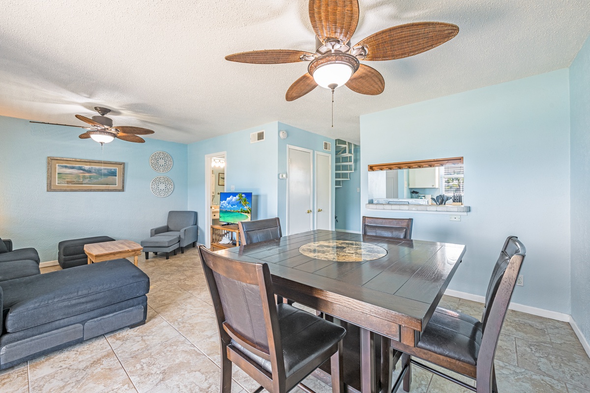 Relax in your coastal-themed living space with comfortable seating, tropical ceiling fans, and an open kitchen perfect for meal prep.
