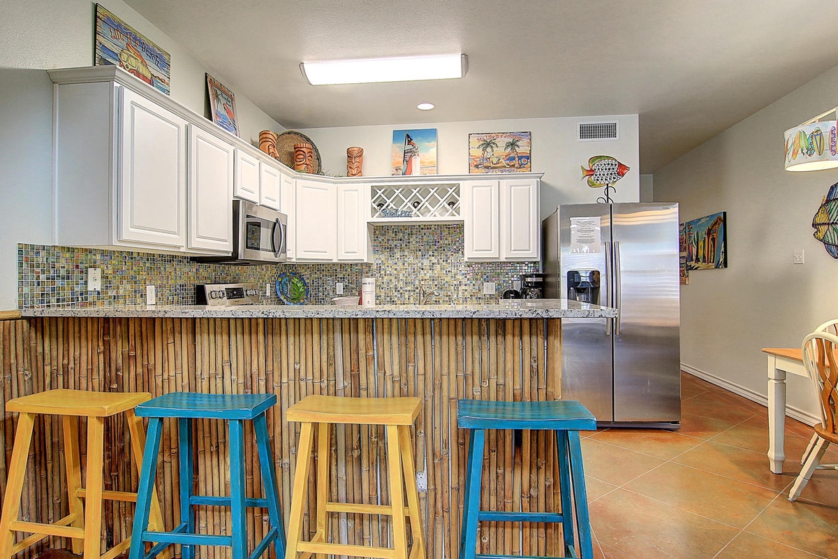 Your tropical-themed kitchen invites culinary adventures with its bamboo breakfast bar, colorful stools, and beach-inspired décor creating the perfect island getaway vibe.