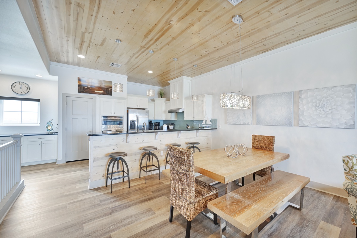Your open-concept kitchen and dining space features warm wood ceilings, modern white cabinetry, and a beautiful island where you'll love preparing meals together.