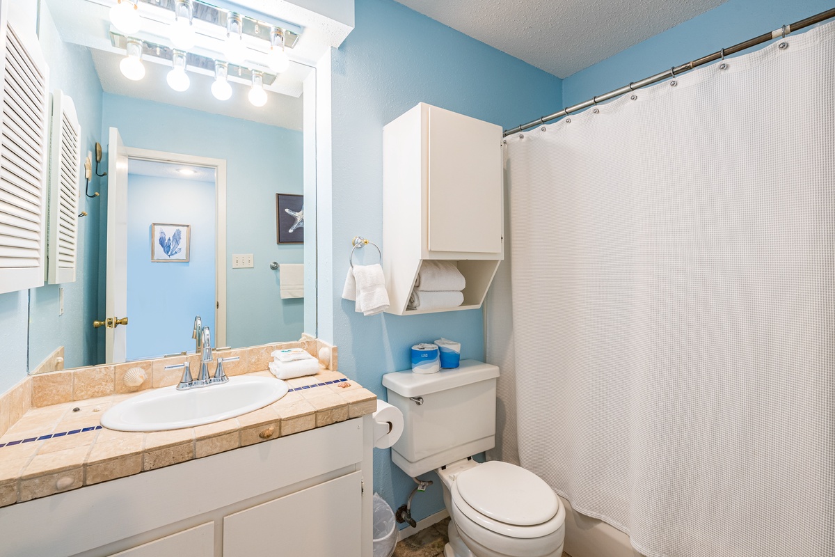 Your private bathroom features coastal-blue walls, marble countertops, and fresh white towels—perfect for refreshing after beach days.