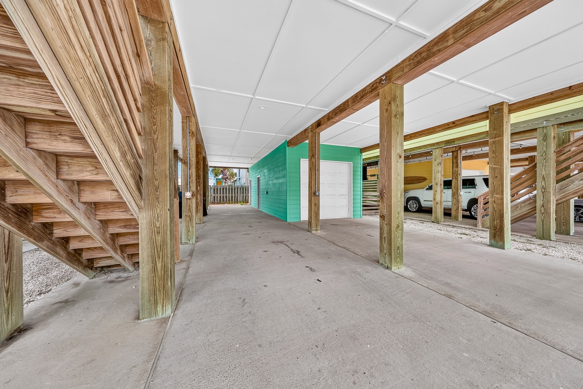 Ground-level parking area with covered carport and easy beach access via outdoor stairway.