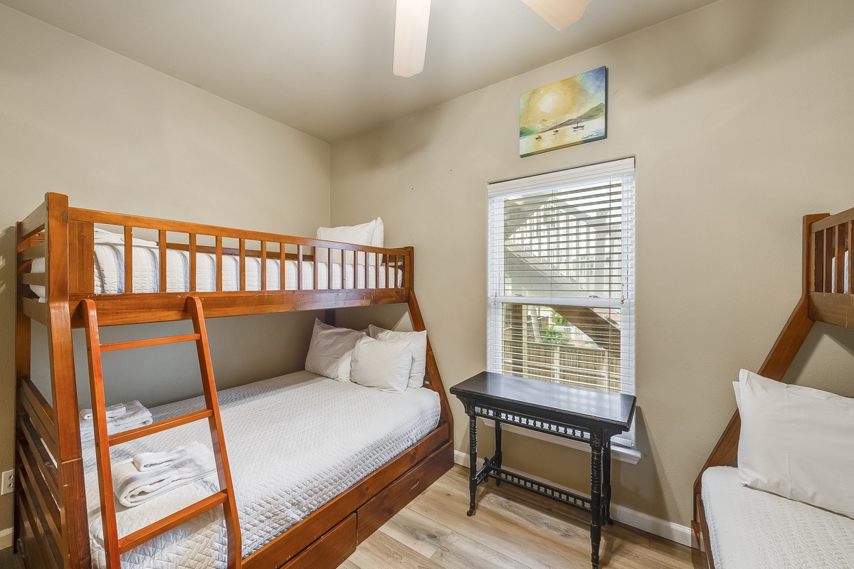 Cozy bunk beds await your family adventure, with crisp linens and a peaceful workspace by the sunny window.