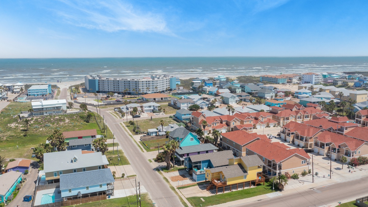 Aerial view of a vibrant coastal community with colorful beach houses, condominiums, and sandy shores along the Gulf Coast.