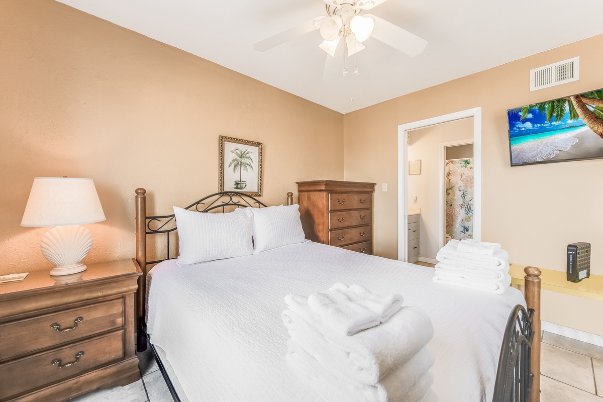 Unwind in your cozy bedroom featuring a comfortable bed with crisp linens and tropical artwork that sets the mood for relaxation.