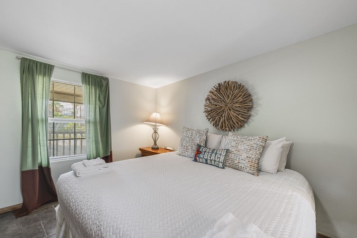 Sink into crisp white linens in your peaceful retreat, where coastal decor and soft lighting create the perfect haven for restful nights.