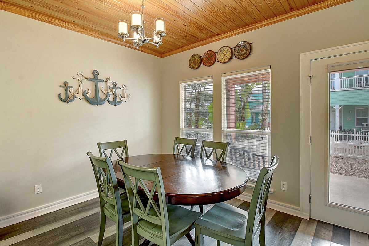 Gather around your charming dining table with coastal touches and warm wood ceiling accents for memorable meals together.
