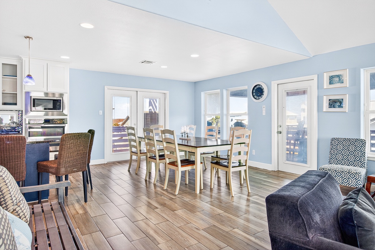 Gather around your spacious dining table where coastal charm meets comfort, with soft blue walls and gleaming floors creating the perfect backdrop.