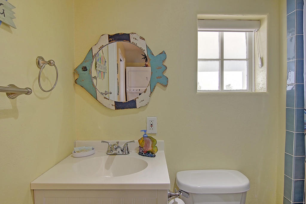 Your charming bathroom features a whimsical fish-shaped mirror and fresh linens, creating a delightful seaside atmosphere for your getaway.