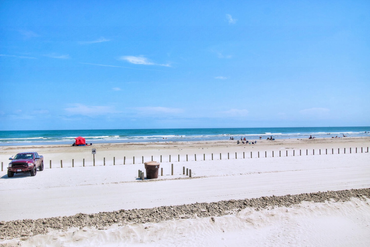 Wide stretch of pristine white sand beach with gentle waves and clear blue skies, perfect for relaxing days by the ocean.