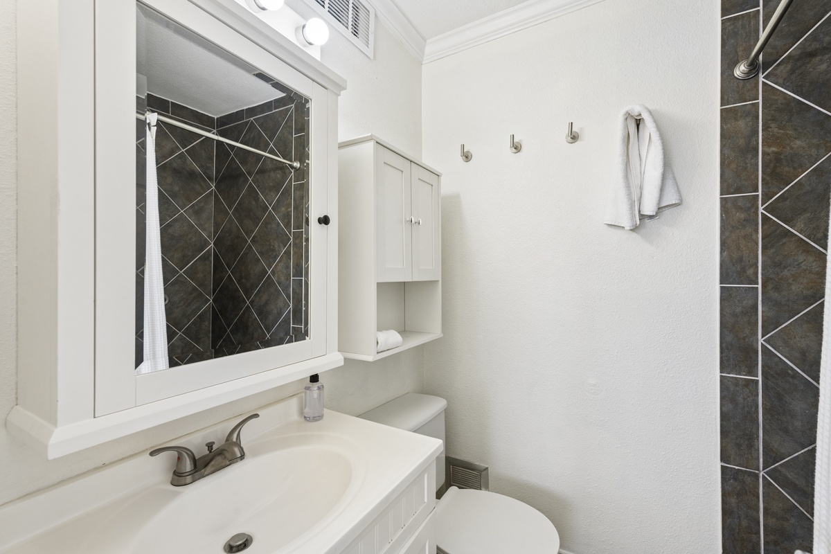 Step into your private bathroom featuring a sleek walk-in shower with elegant dark tile, fresh towels, and modern fixtures. Everything you need for a refreshing start to your day awaits here.