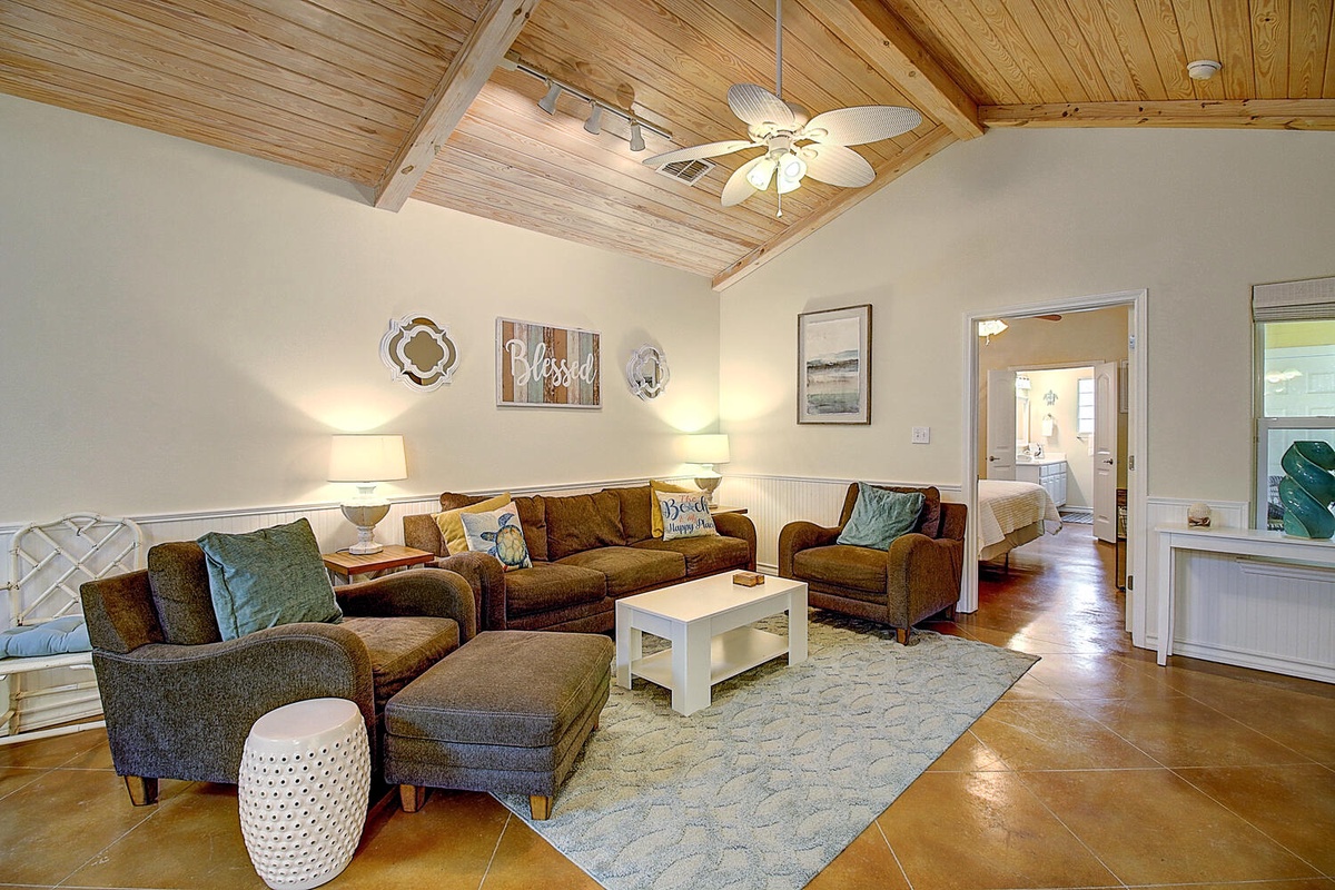 Sink into your cozy living room with vaulted wood ceilings, plush seating, and coastal-inspired touches that invite you to unwind.