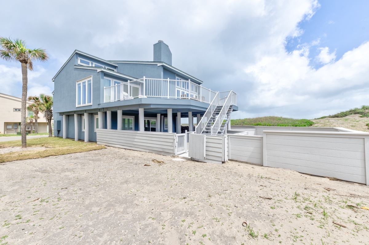 Modern beachfront home with wraparound balcony and coastal charm, steps from sandy shores.