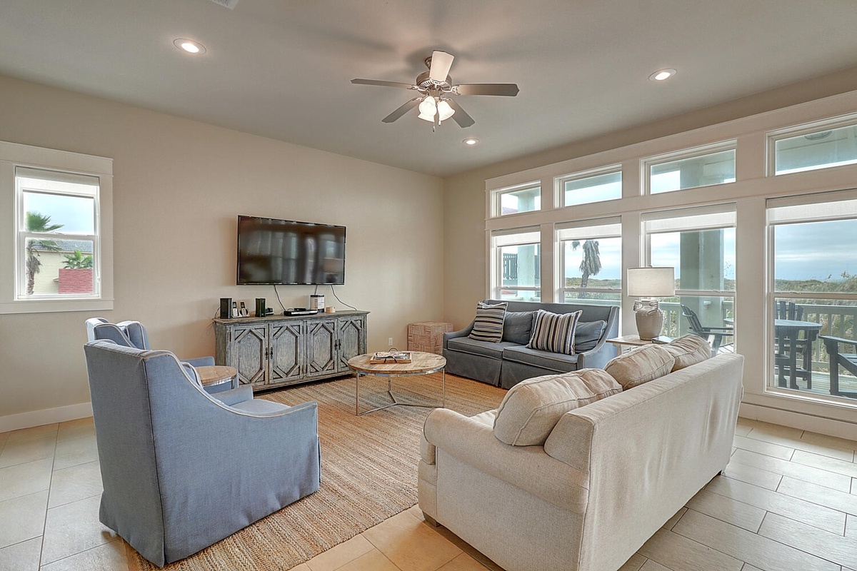 Relax in your bright living space with comfortable seating, large windows, and entertainment center perfect for unwinding after beach days.