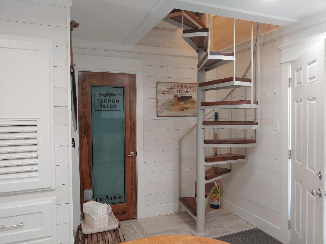 Admire the charming coastal details and nautical artwork as you ascend this elegant spiral staircase to your private upper level retreat.