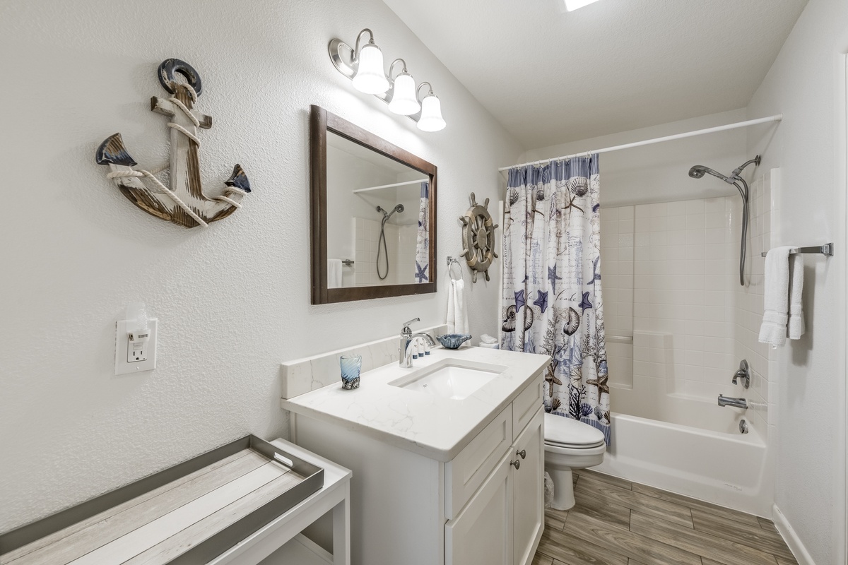 Your private bathroom features coastal charm with nautical décor, a soaking tub with shower, and crisp white finishes that create a refreshing retreat after beach days.