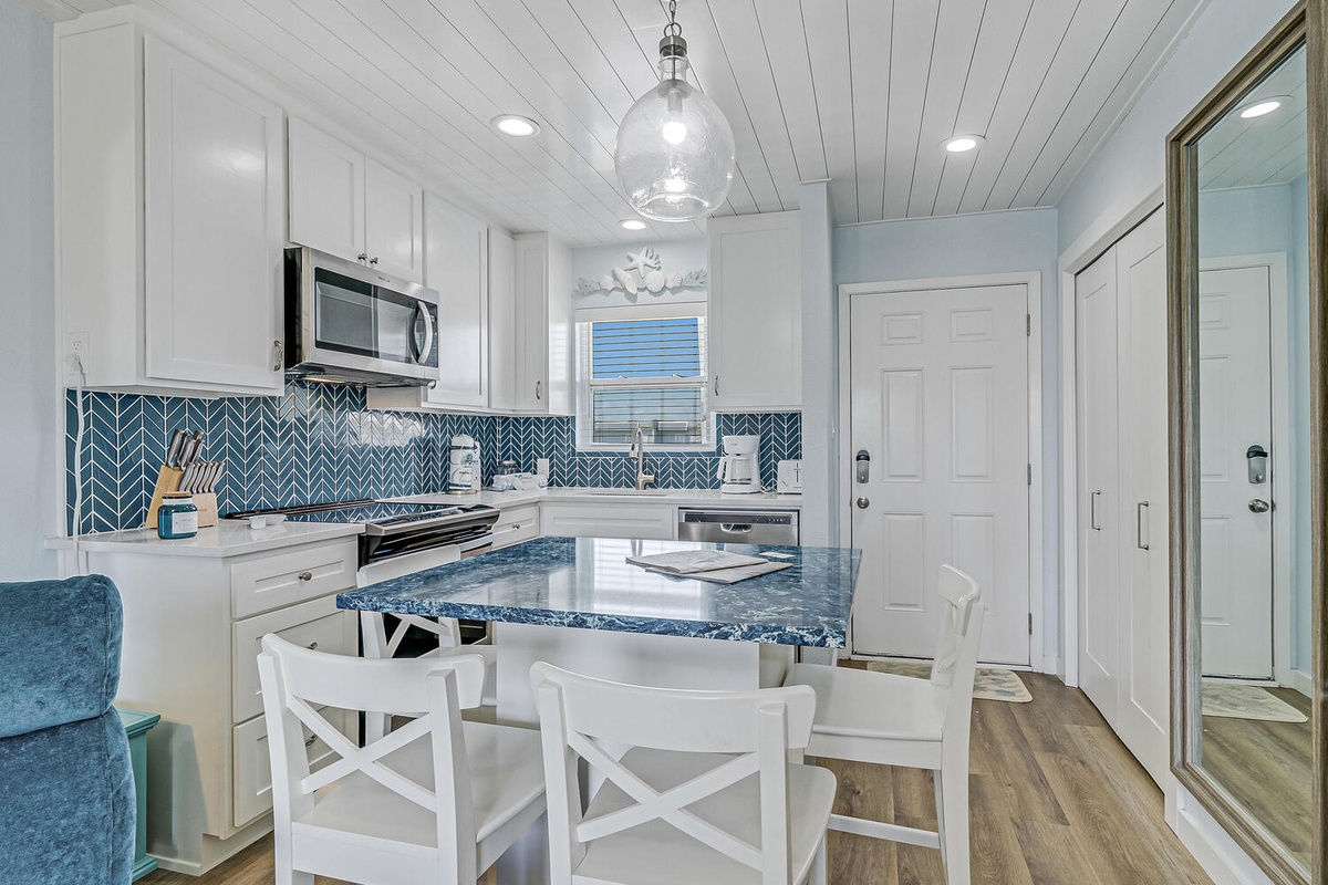 Your coastal kitchen awaits with blue herringbone backsplash, granite island, and white coastal charm perfect for morning coffee or dinner prep.