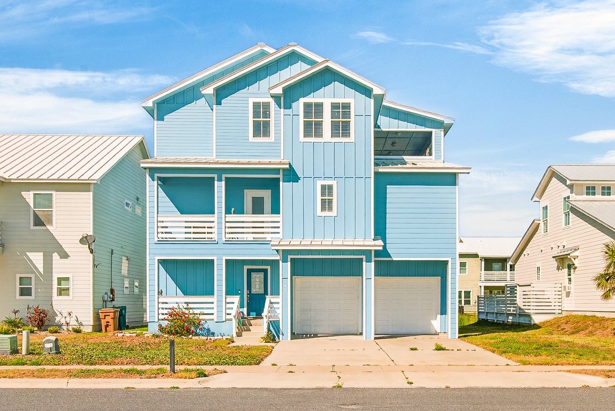 Charming coastal home with bright turquoise siding and white trim in a peaceful neighborhood setting.