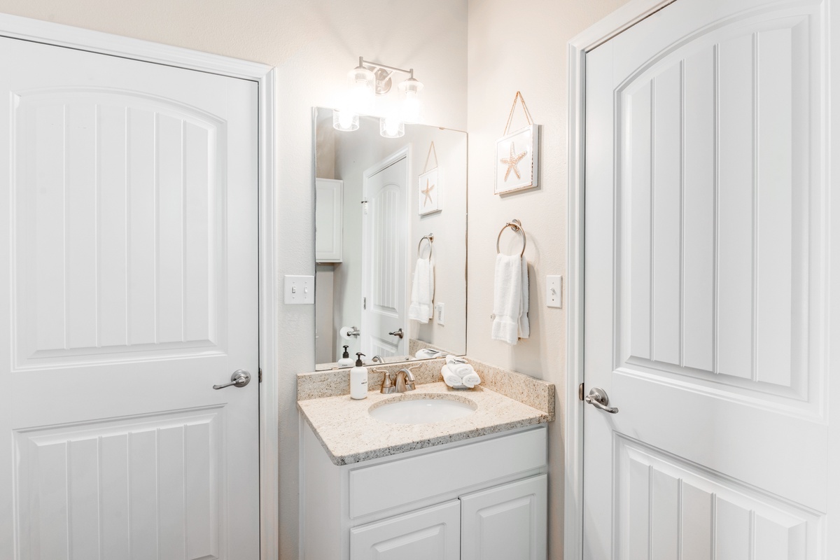 Step into your bright, coastal-themed bathroom where fresh white linens and cheerful starfish art create a serene start to your day.
