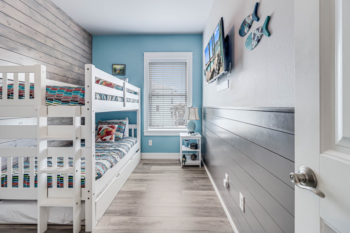 Your kids will love this cheerful bunk room with coastal charm, featuring comfortable beds and playful beach-themed decor.