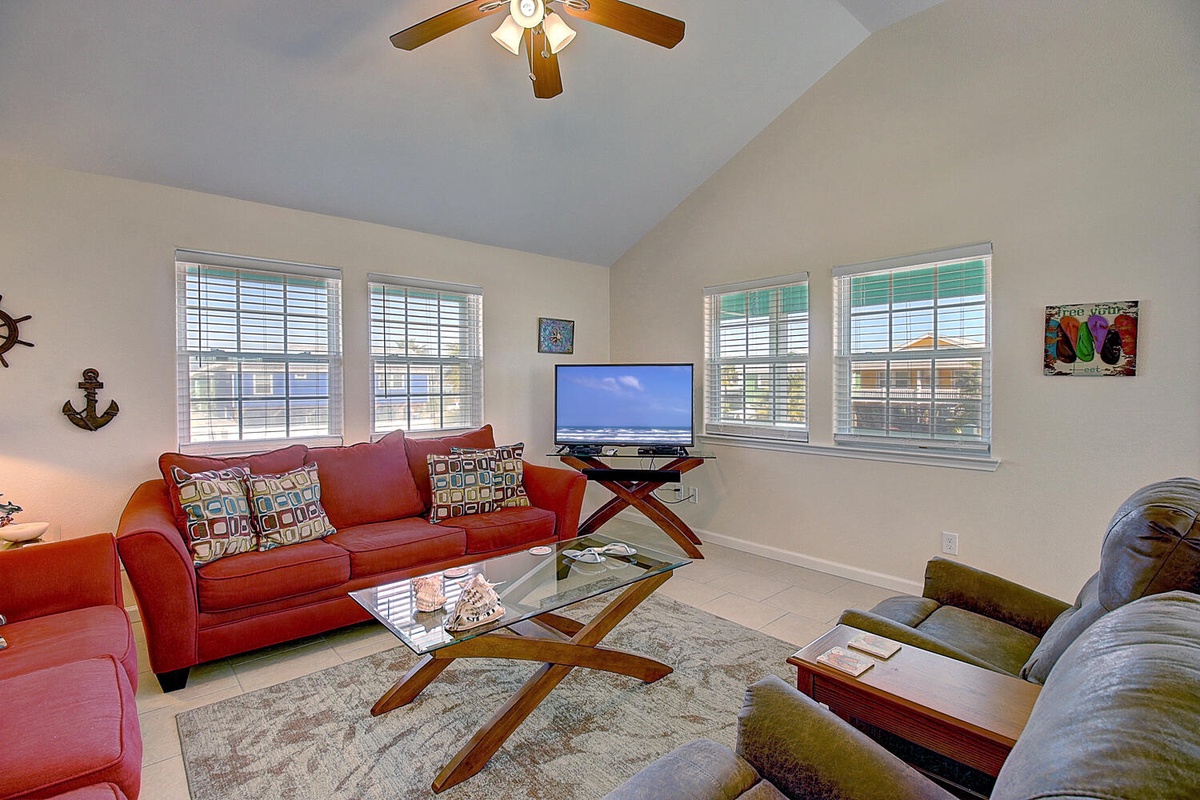 Relax in your bright living space with comfortable seating, ceiling fan, and entertainment center—perfect for unwinding after coastal adventures.