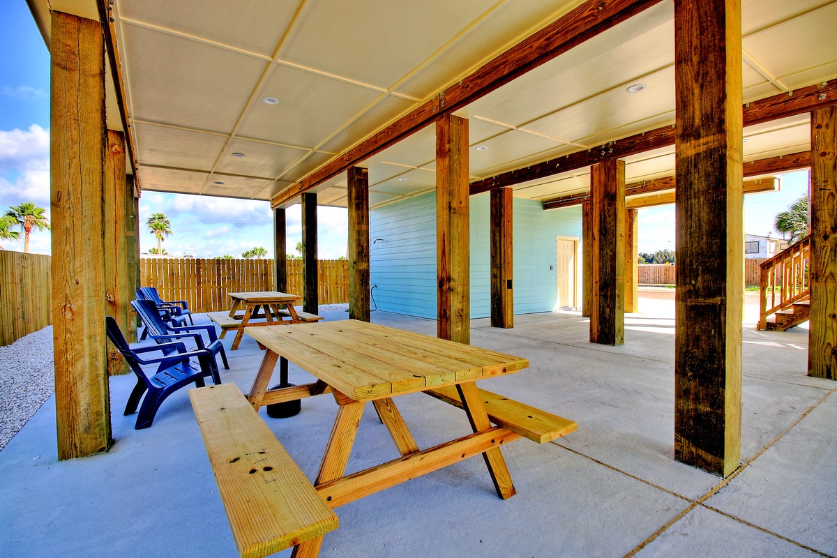 Relax at your covered picnic table with blue Adirondack chairs, perfect for outdoor meals and gathering.