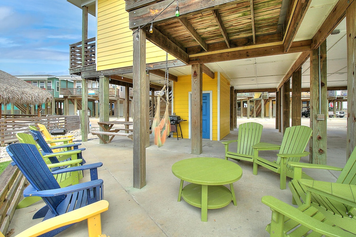 Colorful beach house community with covered seating areas and vibrant vacation rental buildings nearby.