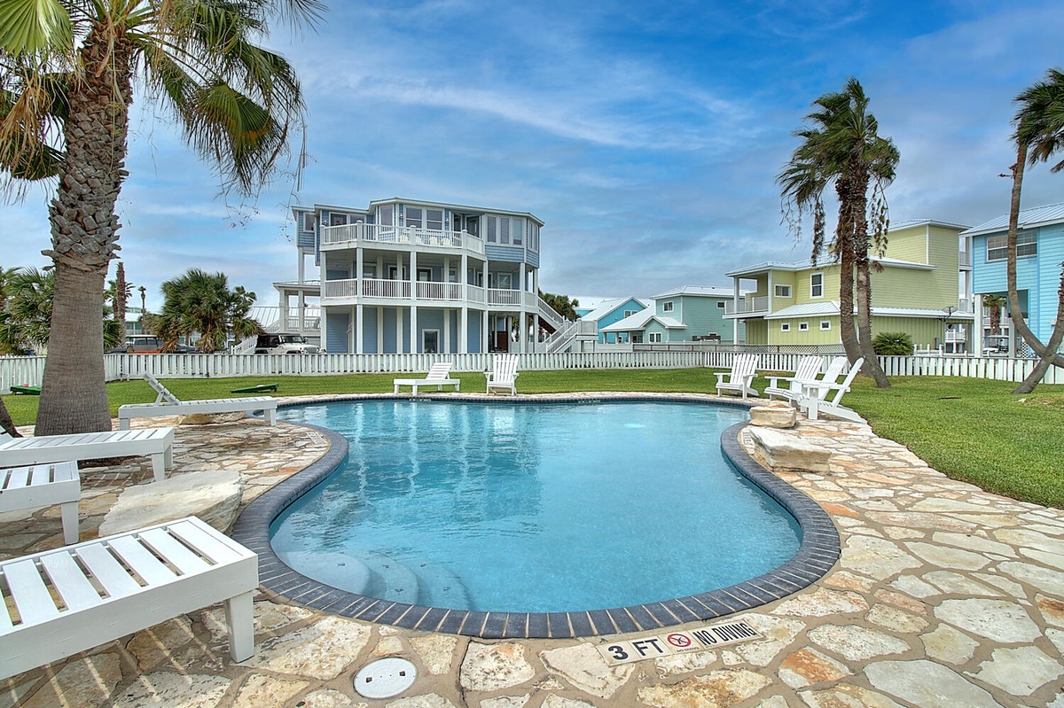 A tropical oasis awaits with crystal-clear waters surrounded by swaying palms and colorful beach houses.