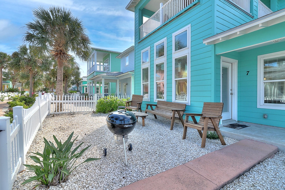 Charming coastal cottage community with vibrant turquoise homes, white picket fencing, and swaying palms creating the perfect beach getaway atmosphere.