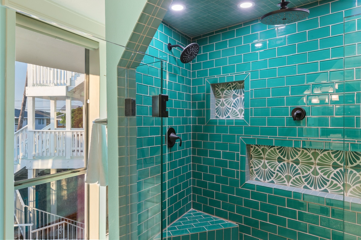 Step into your luxurious tiled shower featuring vibrant turquoise walls and stunning rainfall showerhead for the ultimate relaxation.