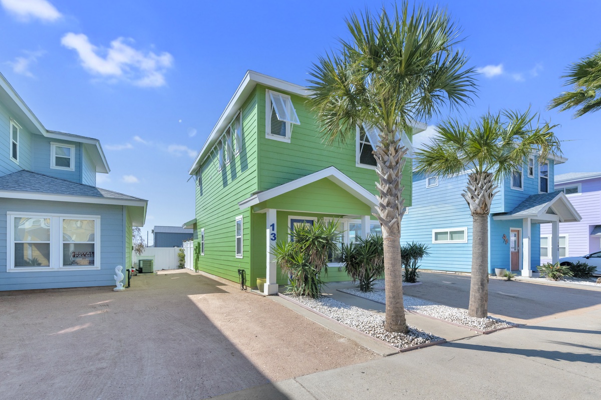 Vibrant green coastal cottage with tropical palms in a colorful beachside neighborhood.