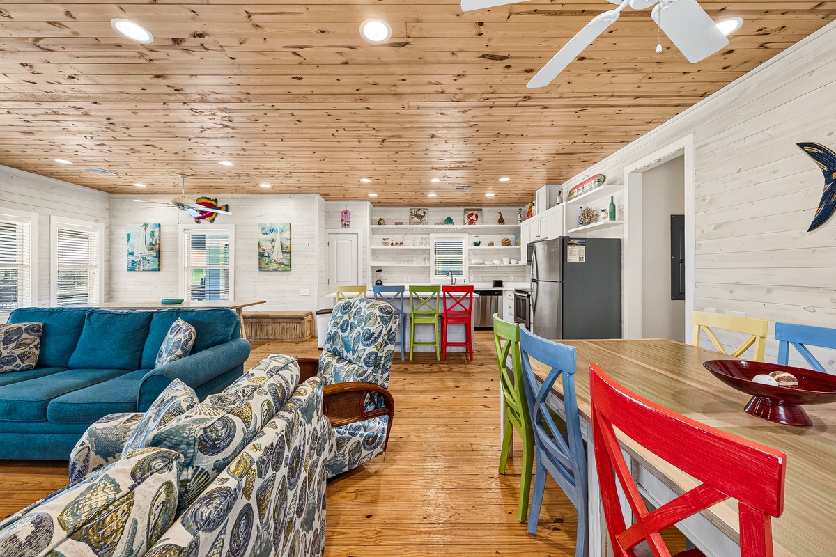 Settle into your spacious open living area where natural wood and playful pops of color create a warm, beachy vibe. The full kitchen and plenty of seating make it easy to gather, relax, and enjoy your coastal getaway together.