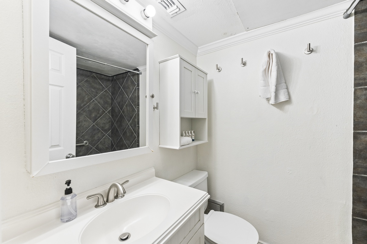 Step into a crisp, modern bathroom designed for your comfort, featuring a sleek vanity, fresh towels, and a beautifully tiled walk-in shower that invites relaxation.