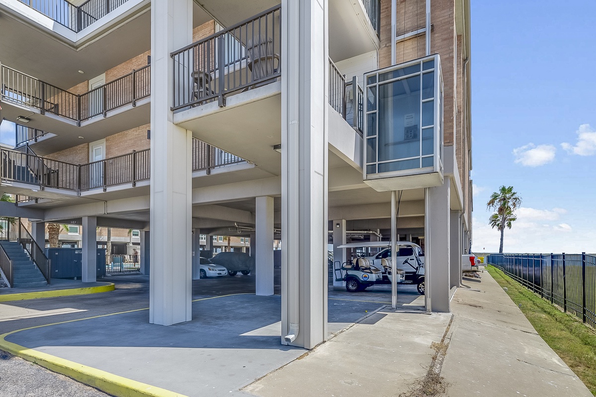 Multi-story beachfront property featuring convenient covered parking and private balconies under clear coastal skies.