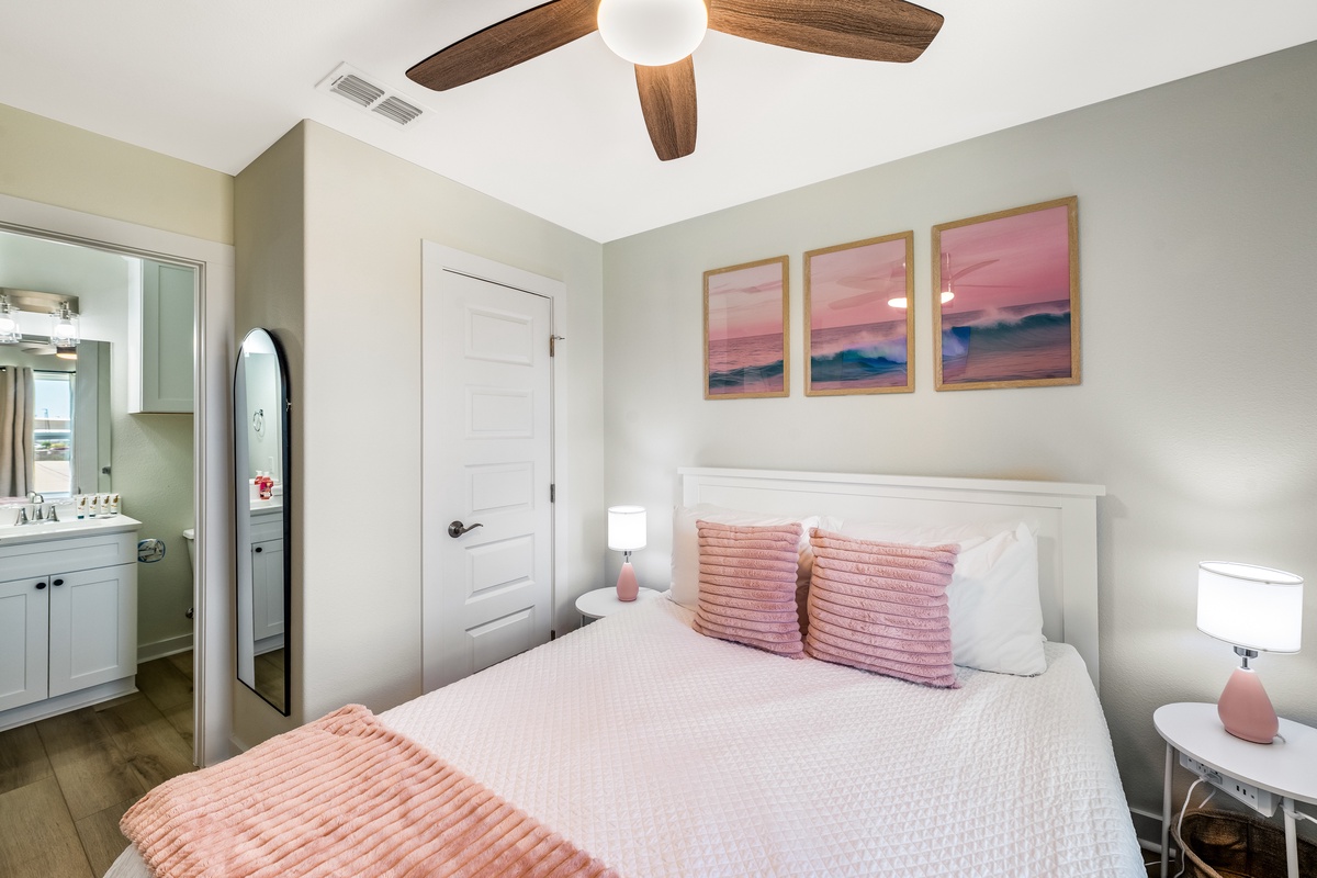 Drift off to sleep under the warm glow of your ceiling fan, surrounded by calming coastal artwork and soft pink accents.