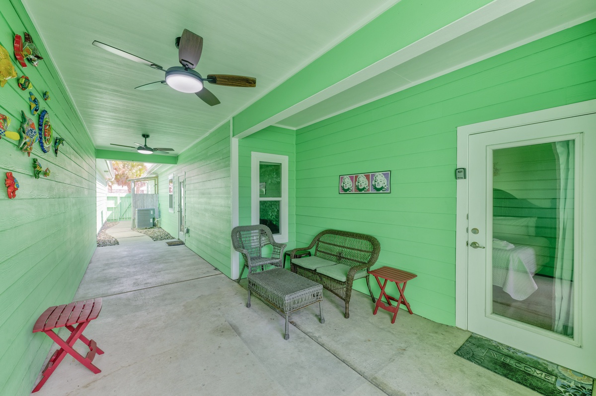 Relax on your vibrant covered patio with wicker seating and colorful folding tables—perfect for morning coffee or evening conversations.