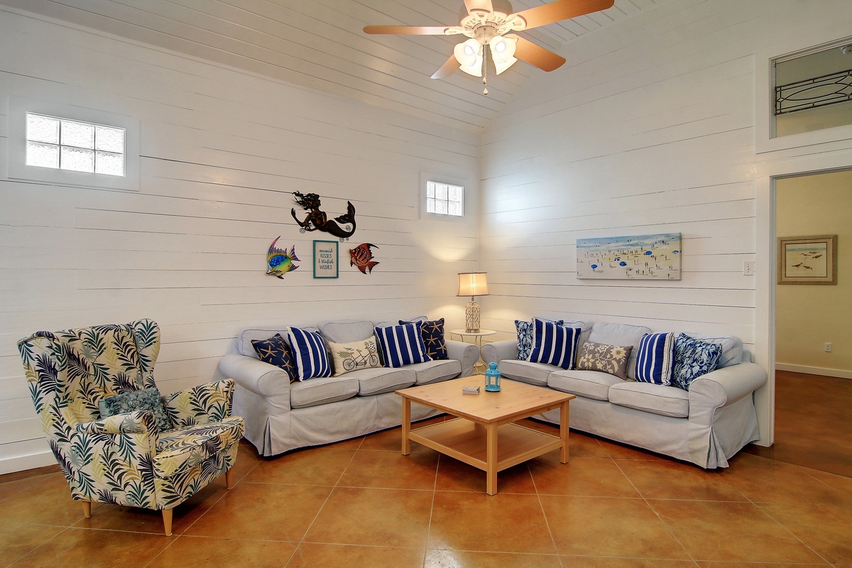 Relax in your bright coastal living room with comfy seating, nautical décor, and a ceiling fan to keep you cool.