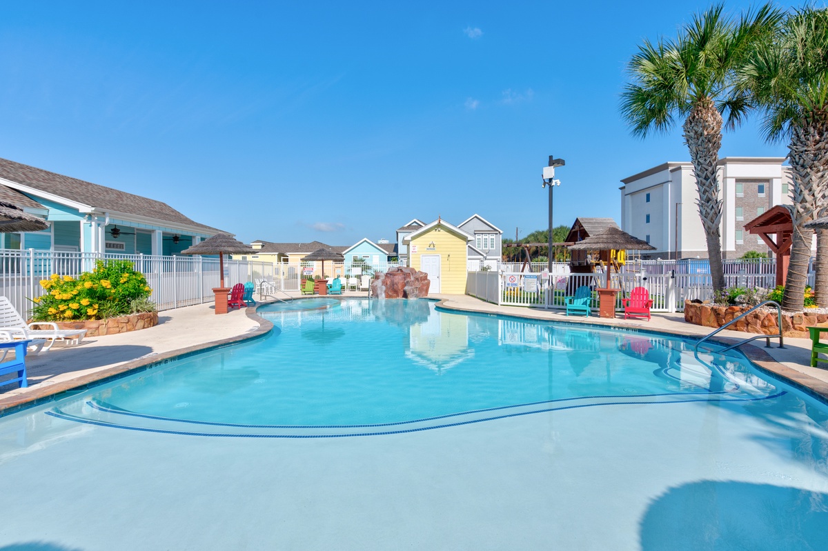 Dive into crystal-clear waters at your resort-style pool, surrounded by colorful beach houses and swaying palms under endless blue skies.