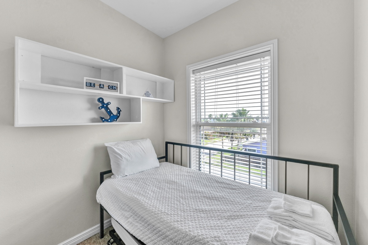 Your cozy bedroom features nautical touches and crisp linens, with natural light streaming through blinds for peaceful mornings.