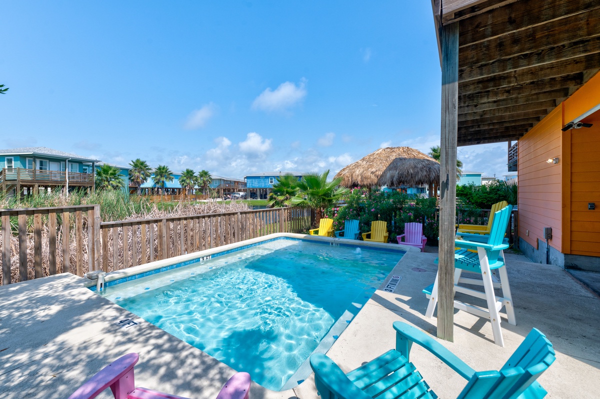 Your private pool oasis awaits with vibrant poolside chairs and tropical tiki hut shade for the perfect beach vacation retreat.